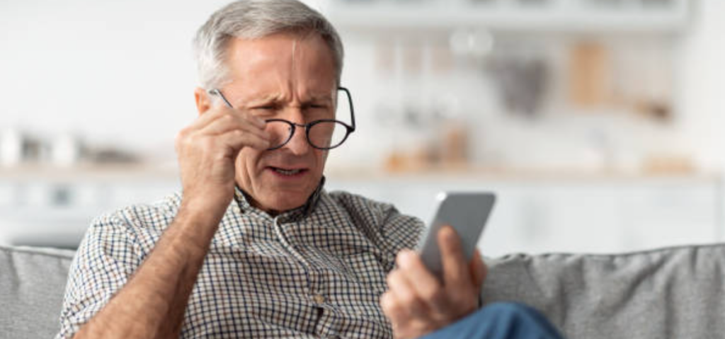 Picture of a man struggling to read something on his phone with his glasses